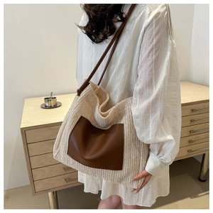 Macro detail of cream woven tote with brown leather pocket and slim shoulder straps