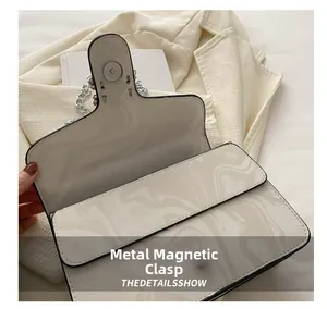 Detail of white marble print handbag featuring a secure silver magnetic snap closure