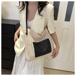 Detail of woven tote bag featuring a contrast black faux leather pocket and slim strap