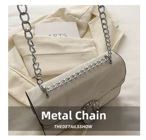 Detail showing the silver chunky chain and rhinestone buckle on marble pattern bag