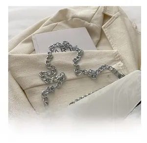 Detail of white marble textured bag with oversized square rhinestone buckle and silver chain