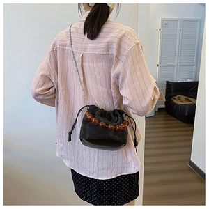 Détail du sac seau noir à cordon avec perles ambrées et bandoulière en chaîne