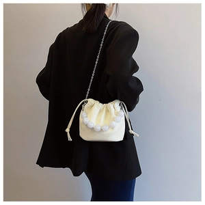 Détail du sac seau blanc à cordon avec poignée perlée et bandoulière en chaîne