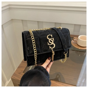 Detail of black quilted velvet flap bag featuring gold SS logo and chain strap