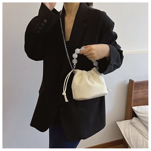 Détail du sac seau crème avec poignée en perles transparentes et bandoulière chaîne