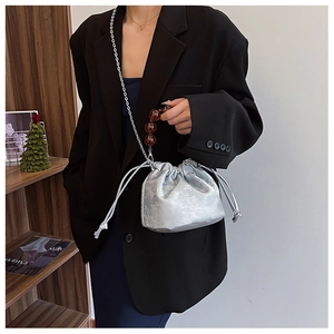 Sac seau argenté avec poignée perlée et bandoulière sur une veste de costume