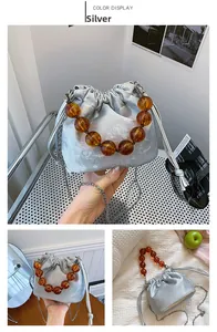 Détail du sac seau argenté avec poignée en perles ambrées et texture satinée