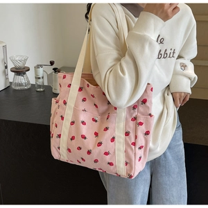Détail du sac cabas en velours côtelé rose avec imprimé fraise et poche à bouton