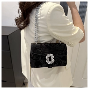 Detail of black marble textured patent leather crossbody bag with sparkling crystal buckle