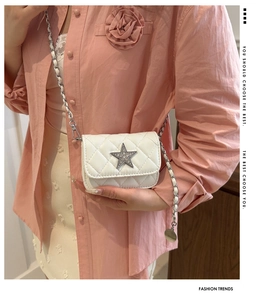 Close-up of white quilted mini bag featuring silver star rhinestone and chain strap