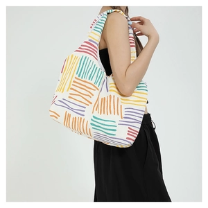 Borsa tote in tela a righe colorate indossata da una modella su sfondo grigio chiaro