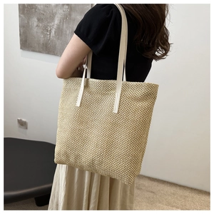 Detailed texture of hand-woven straw tote bag with premium white leather handles