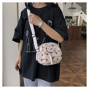 Detail of white corduroy crossbody bag with cute strawberry pattern and adjustable strap