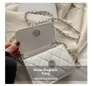 Close-up of the secure silver magnetic snap closure on a white quilted crossbody bag