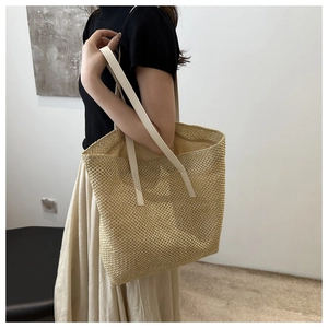 Close-up of woven straw tote bag with beige leather handles for summer vacation