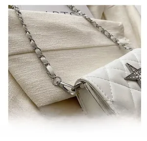 Detail of silver metal hook and chain on white quilted leather mini crossbody bag