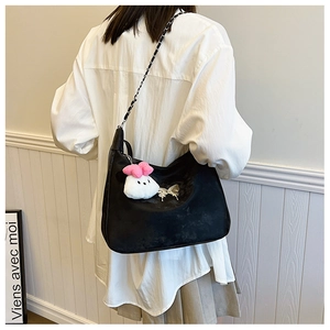 Detail of a large black tote bag with chain strap and cute bunny pendant on model