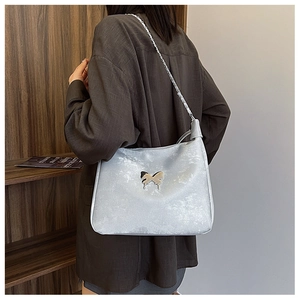 Detail of light blue hobo bag with a gold butterfly buckle shown on model shoulder