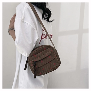 Brown corduroy crossbody bag with red strawberry pattern shown on a model