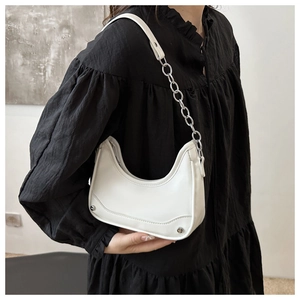 Close-up of white hobo bag with silver chain strap and metal rivet details on model