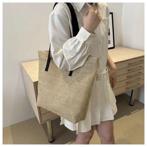 Detail of woven straw tote bag texture with elegant black leather shoulder straps