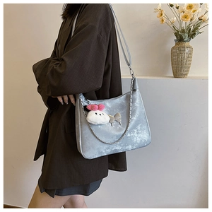 Detail of silver metallic bag with chain trim, butterfly charm and plush rabbit pendant