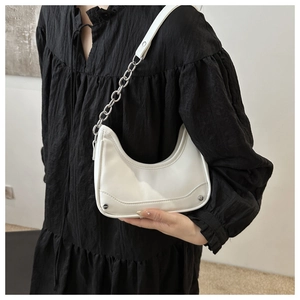 Detail of white moon-shaped hobo bag with silver chain strap worn over the shoulder