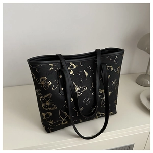Detail of embroidered gold butterflies on a large black leather tote bag for women