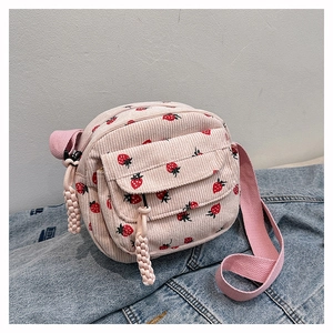 Detail of pink corduroy crossbody bag featuring red strawberry patterns and a front pocket
