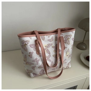 Detail view of butterfly print tote bag with pink leather handles and gold rivet accents