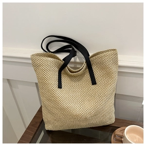 Beige hollow woven tote bag with black shoulder straps and spacious casual design