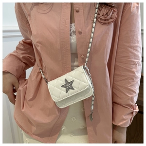 Detail of white quilted mini bag with silver star crystal and chain strap on model