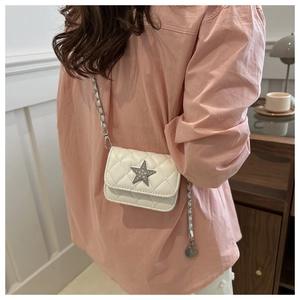 Detail of white quilted mini crossbody bag with a star charm and chain strap