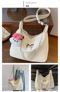 Detail of off-white hobo bag with silver butterfly accent and plush toy charm