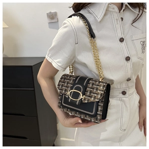 Detail view of a vintage woven tweed crossbody bag with a gold buckle on a model