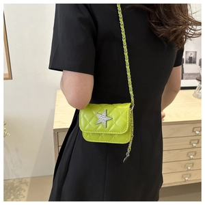 Close-up of neon green quilted mini bag with silver star buckle worn on a black dress