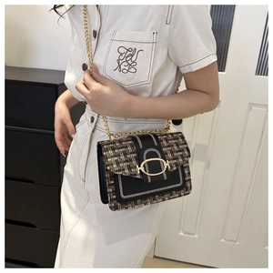 Detailed view of tweed fabric texture and gold metal buckle on a small square crossbody bag