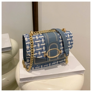 Detail of tweed texture and golden horseshoe buckle on the elegant blue chain bag