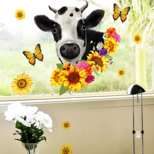 Detailed view of sunflower and cow window stickers on a raindrop-covered glass surface