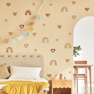 Vue détaillée de stickers muraux arc-en-ciel et cœur aux tons chauds dans une chambre