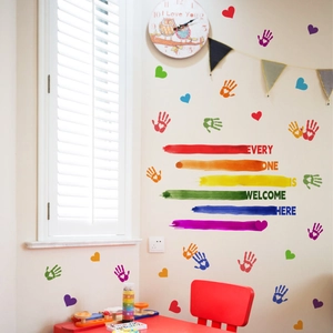 Detail of Everyone Is Welcome Here wall decals with rainbow hearts and colorful handprints