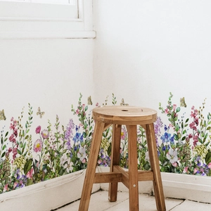 Detail of colorful wildflower wall stickers with butterflies on a white wall and wood stool