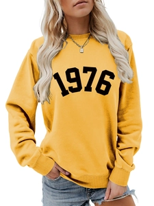 Close-up of ginger yellow crewneck sweatshirt featuring a bold black 1976 numeric print