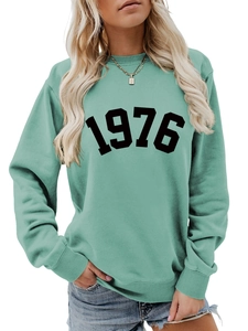 Detailed close-up of mint green crewneck sweatshirt with retro 1976 black print
