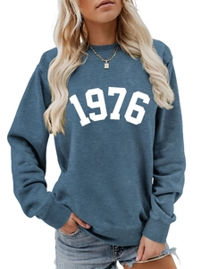 Detail of blue crewneck sweatshirt featuring white 1976 print and ribbed cuffs