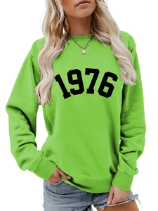 Detail of neon green crewneck sweatshirt featuring a bold black 1976 vintage print