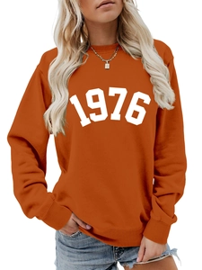 Close-up of orange sweatshirt showing white 1976 printed text and cotton fabric details