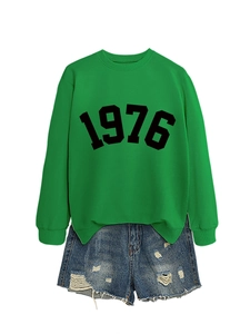 Close-up of green 1976 printed sweatshirt paired with distressed blue denim shorts
