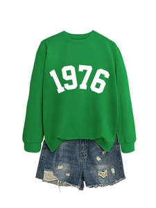 Detailed flat lay of green sweatshirt with 1976 print and distressed denim shorts