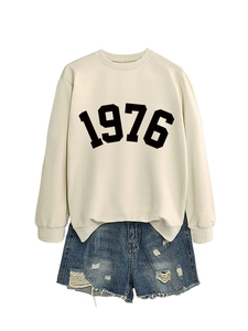 Detail of round neck sweatshirt with 1976 print and side slit hem paired with denim shorts